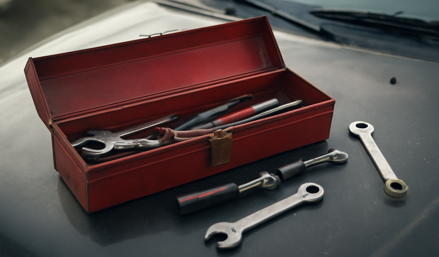 boîte à outils et pièces posées sur capot