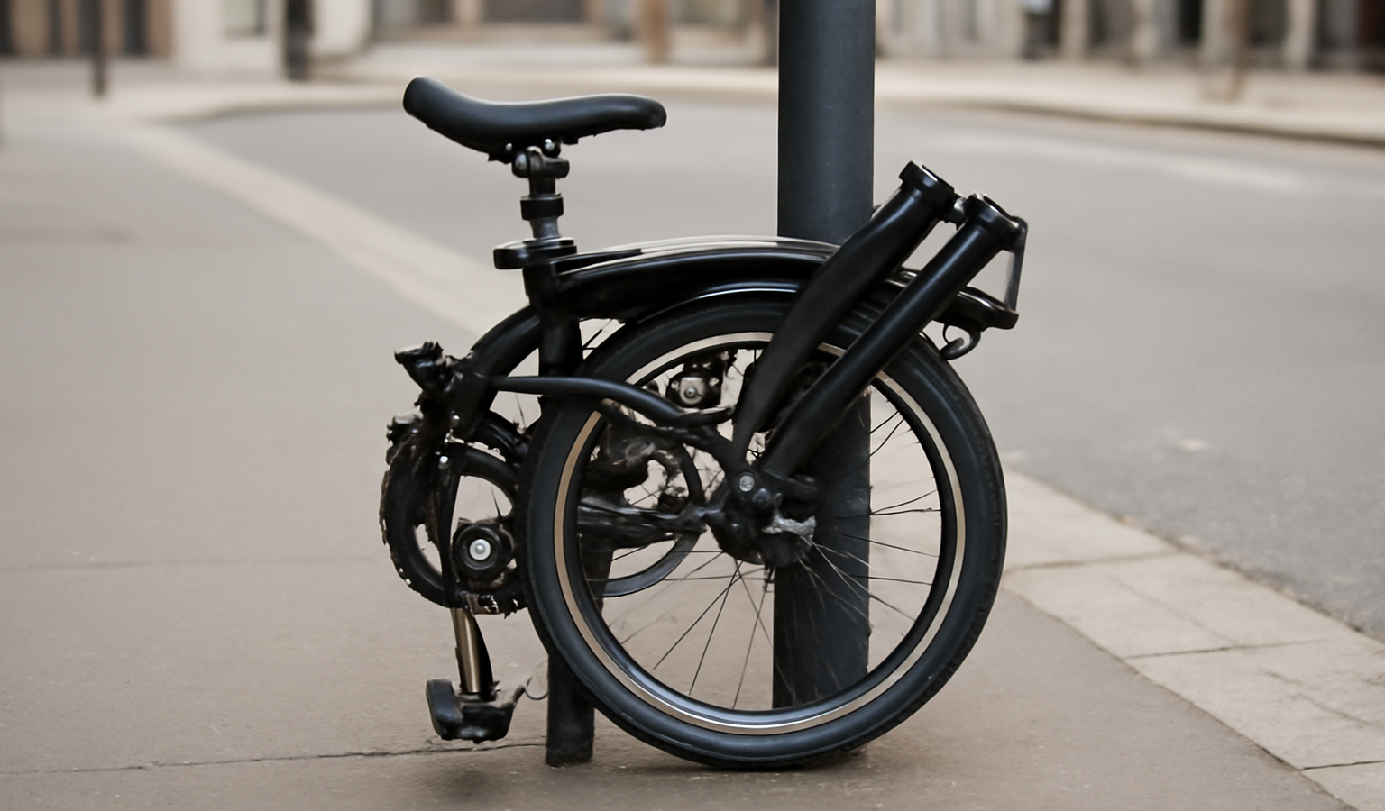 vélo pliant verrouillé sur un poteau urbain