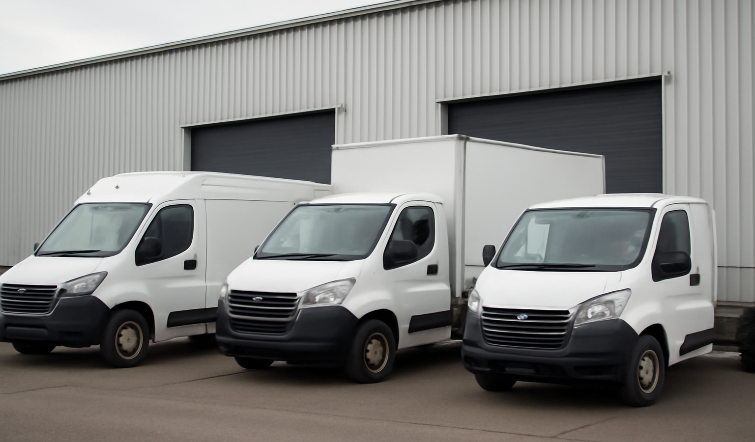 plusieurs vehicules utilitaires gares devant entrepot