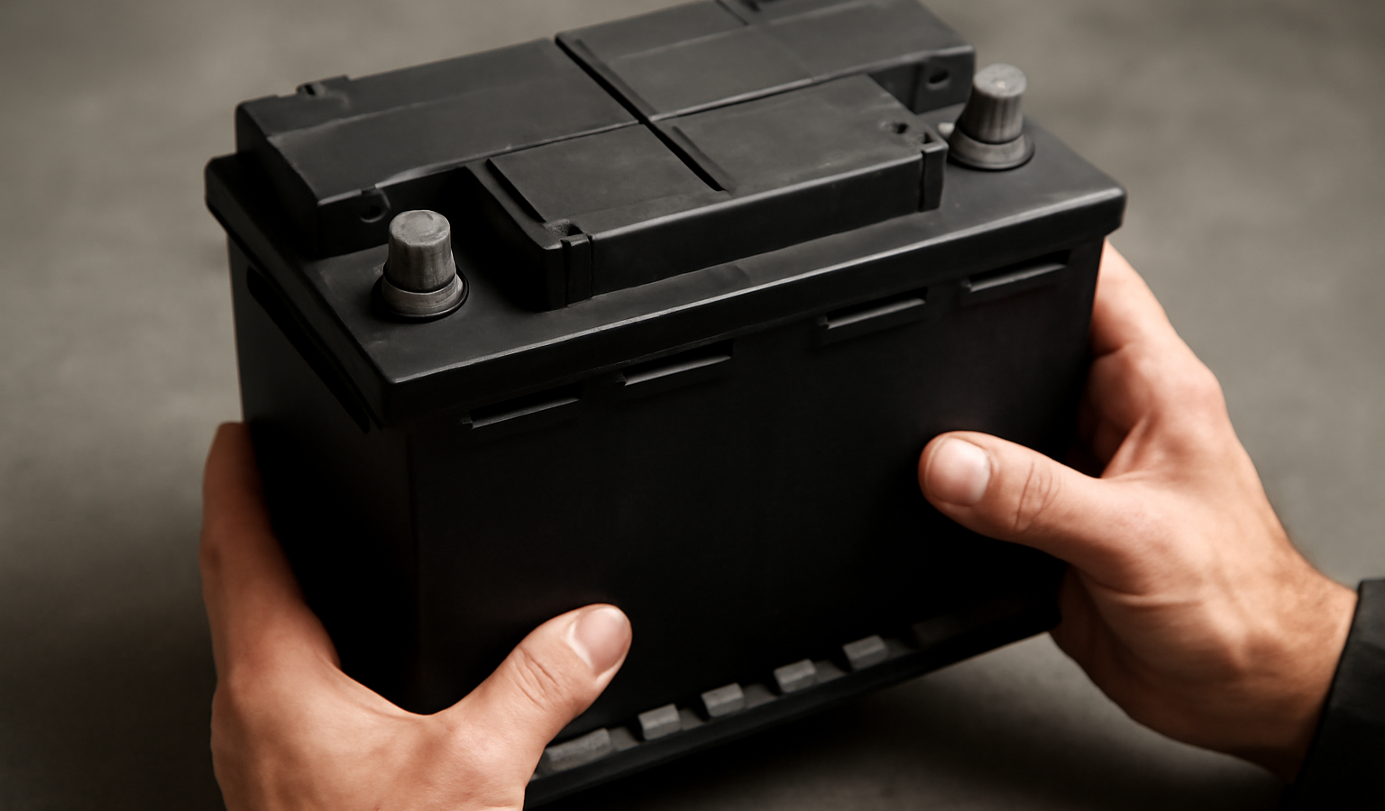mains tenant une batterie automobile